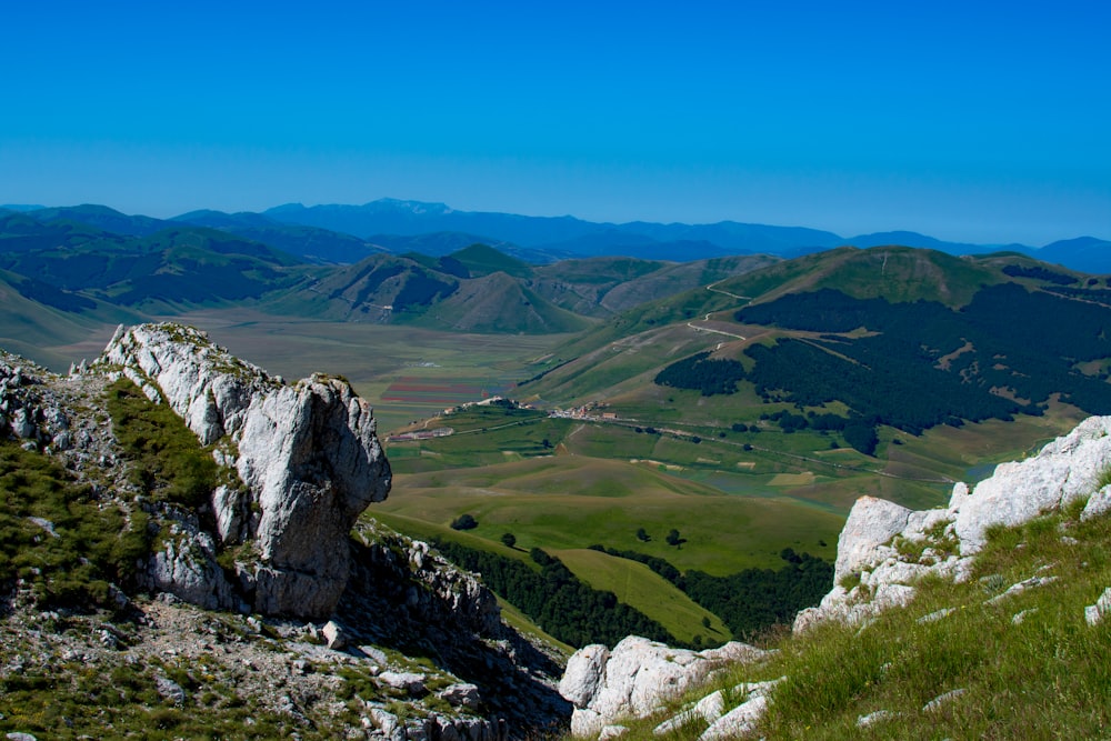 green grass field and gray rocky mountain during daytime