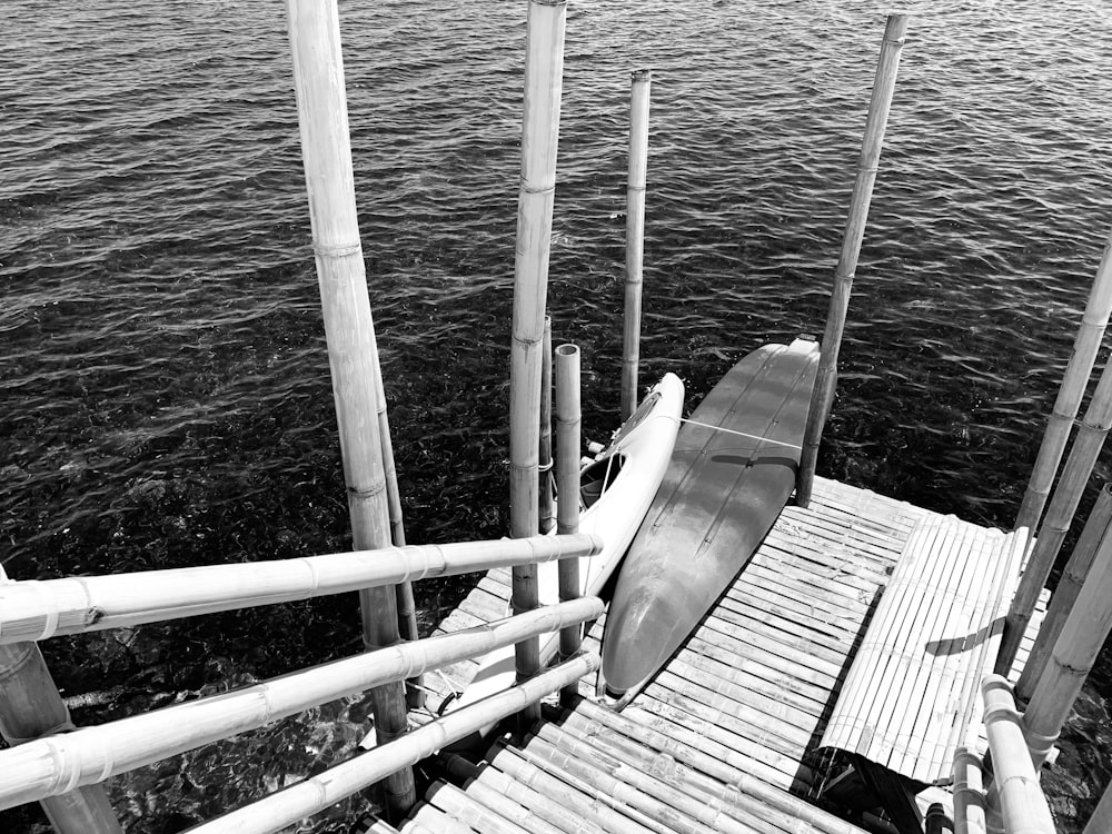 grayscale photo of a boat on a wooden dock