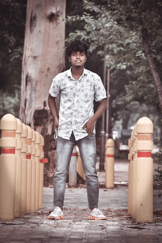 man in white and black floral shirt and blue denim jeans standing beside brown wooden barrels in Chandigarh India