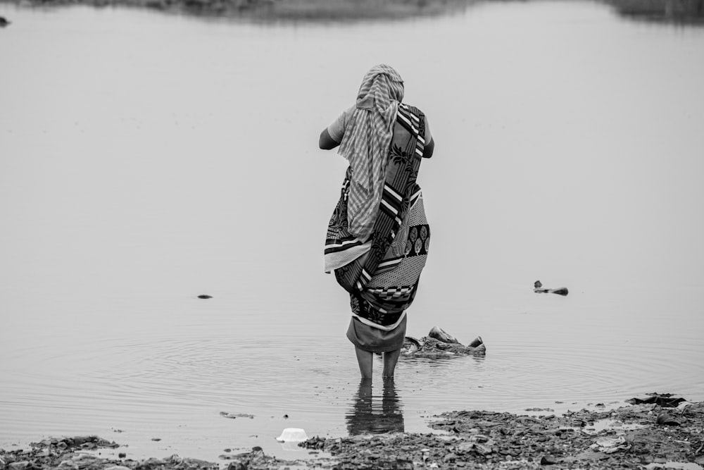 woman in black and white stripe dress walking on wet sand