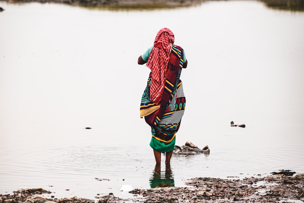 woman in red and green dress walking on beach during daytime