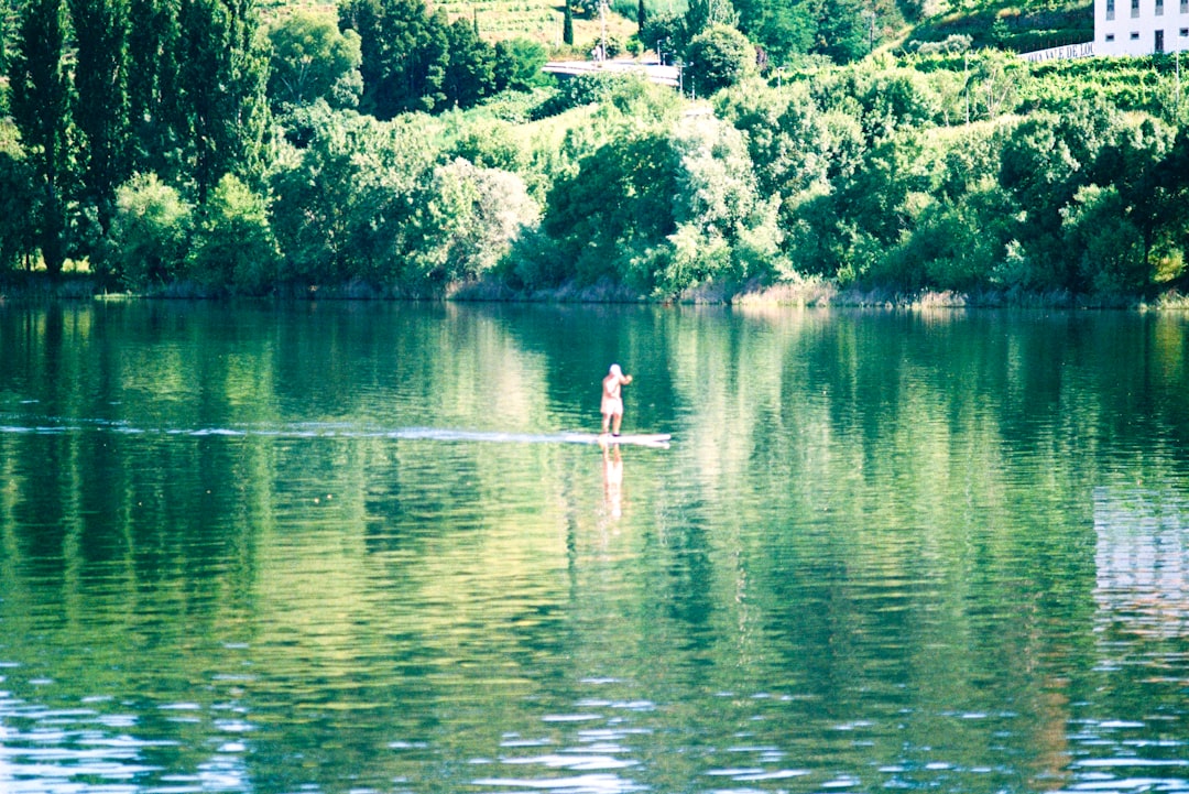 woman in white shirt and blue shorts on white boat on lake during daytime