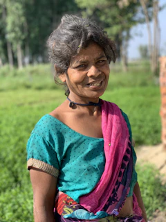 A woman wearing a soft pastel kurti, smiling in natural sunlight on a city street