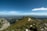A scenic view of a lush mountain landscape with a winding trail and clear blue skies.