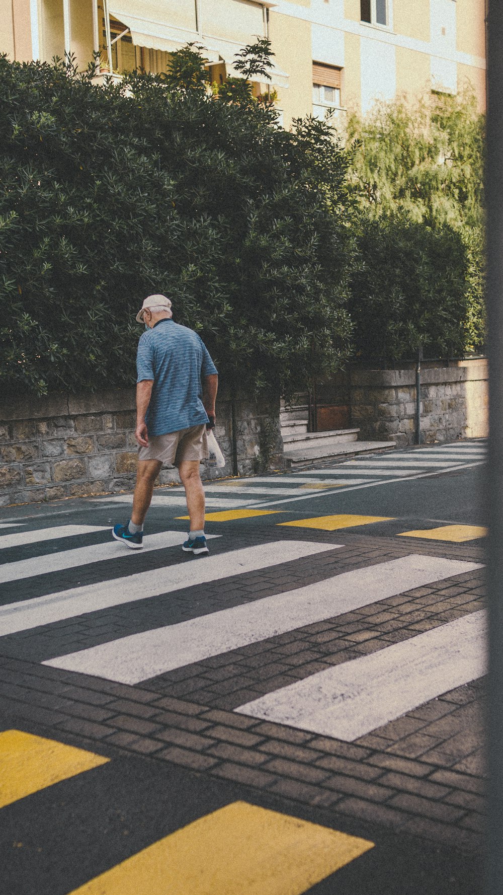 Homme en t-shirt bleu et short marron marchant sur une voie piétonne pendant la journée