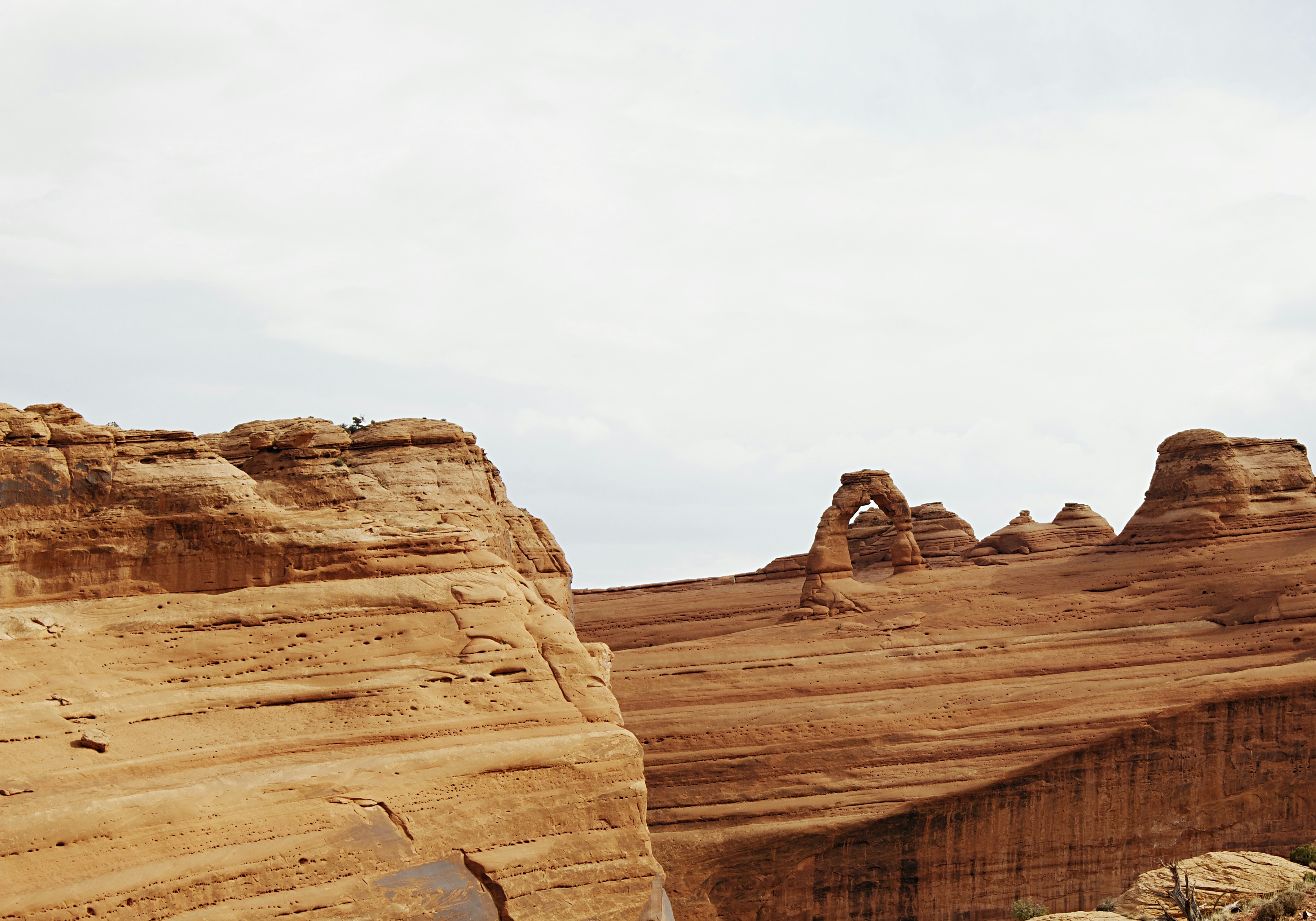 brown rock formation under white sky during daytime, The famous Delicate Arch from afar.