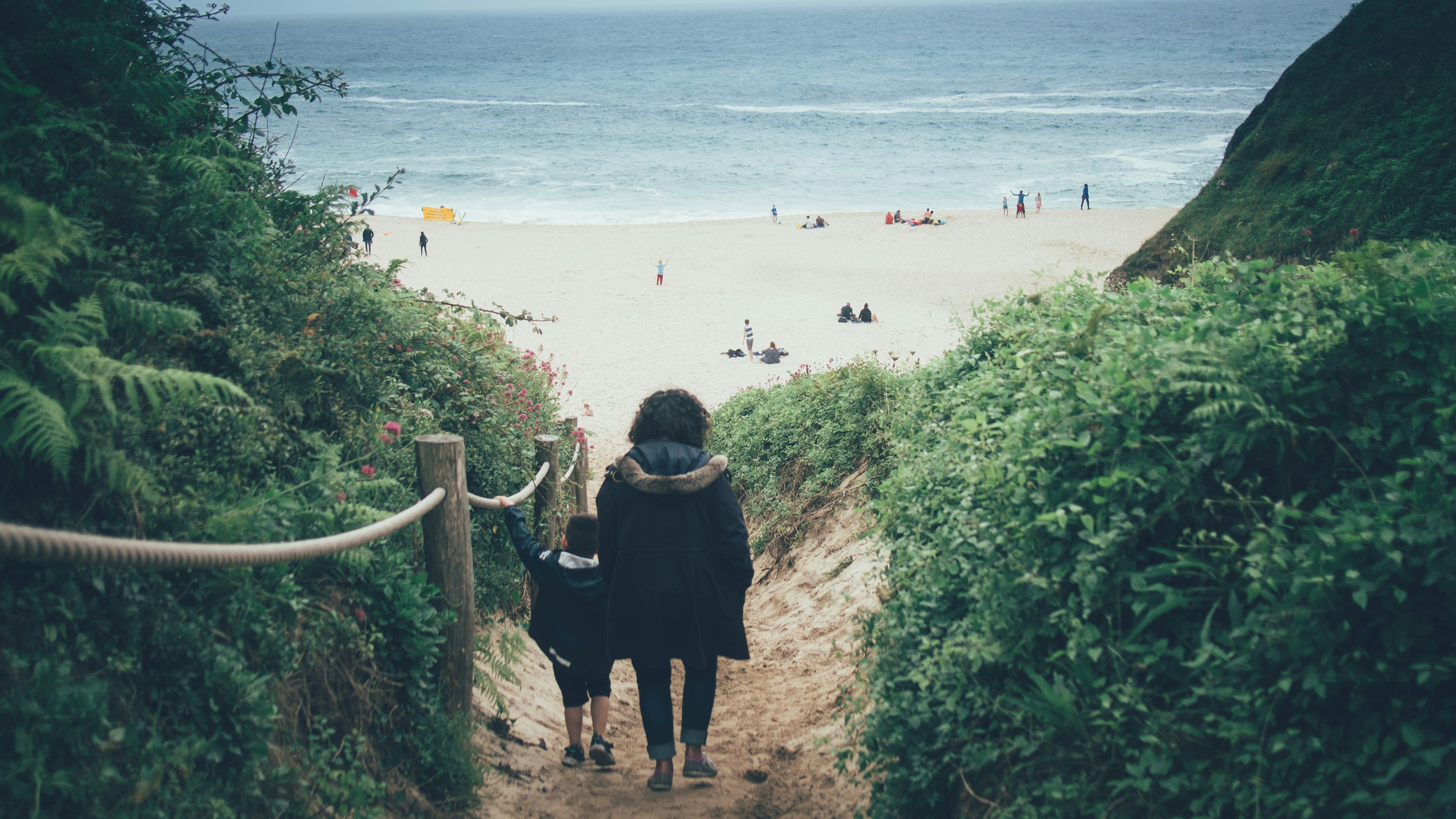 woman in black dress standing on beach during daytime, Going to the beach, at Porthcorno, Cornwall.