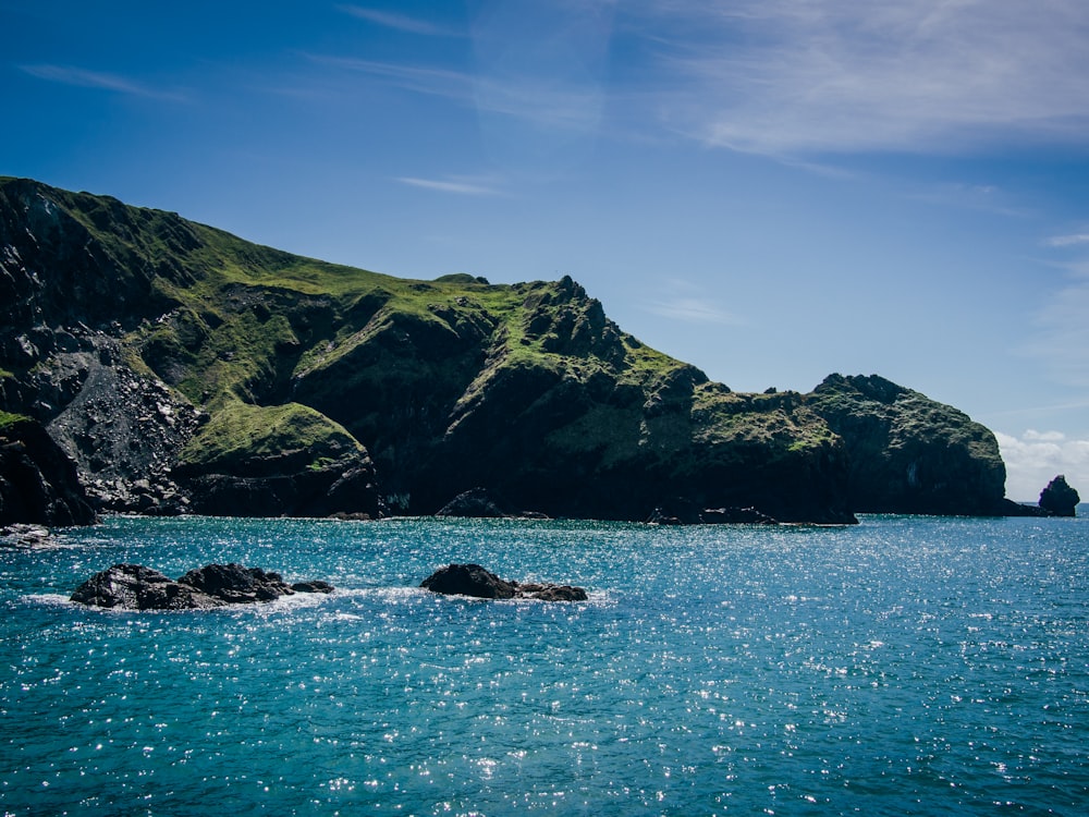 green mountain beside body of water during daytime