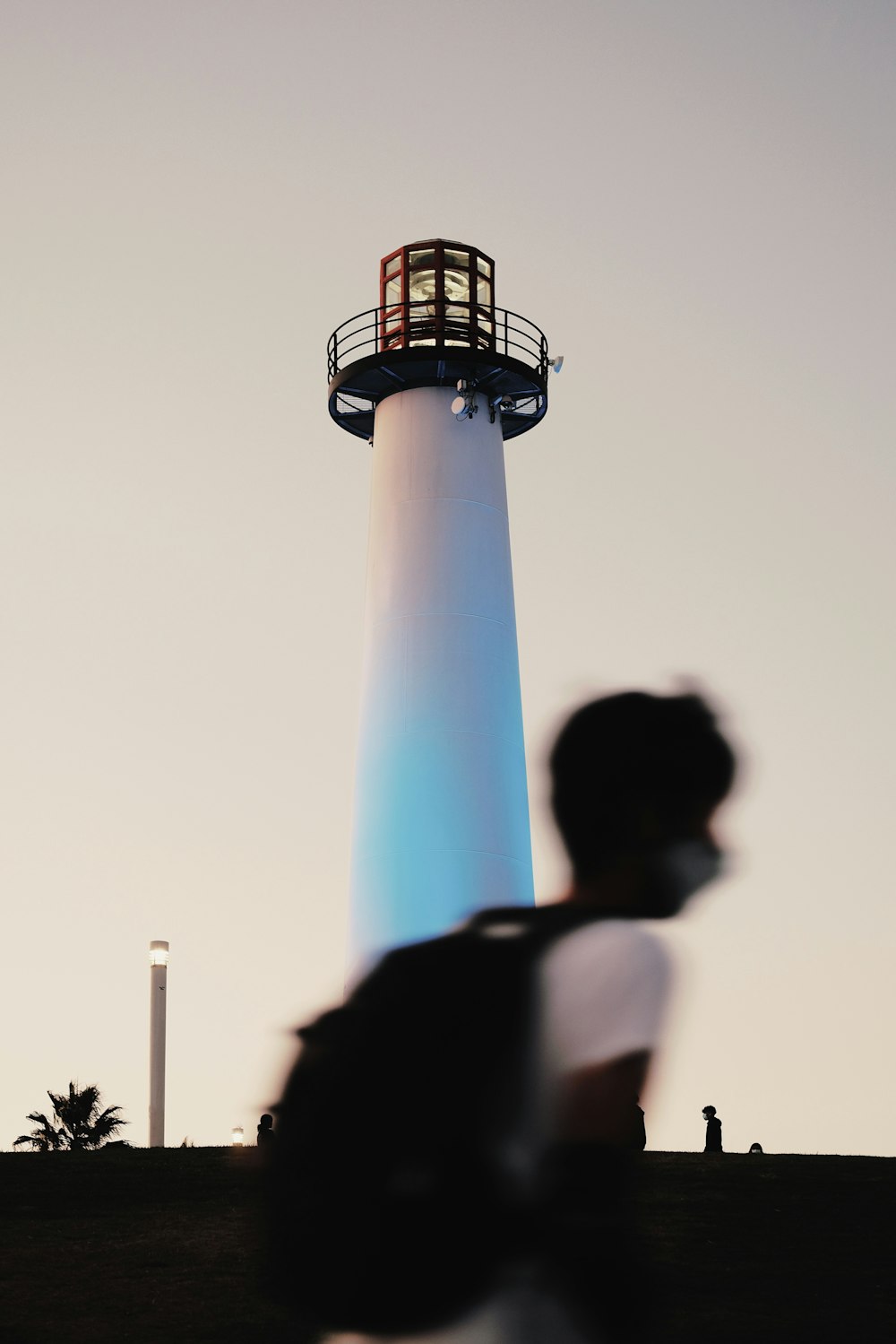 man in white t-shirt standing near white and blue tower during daytime