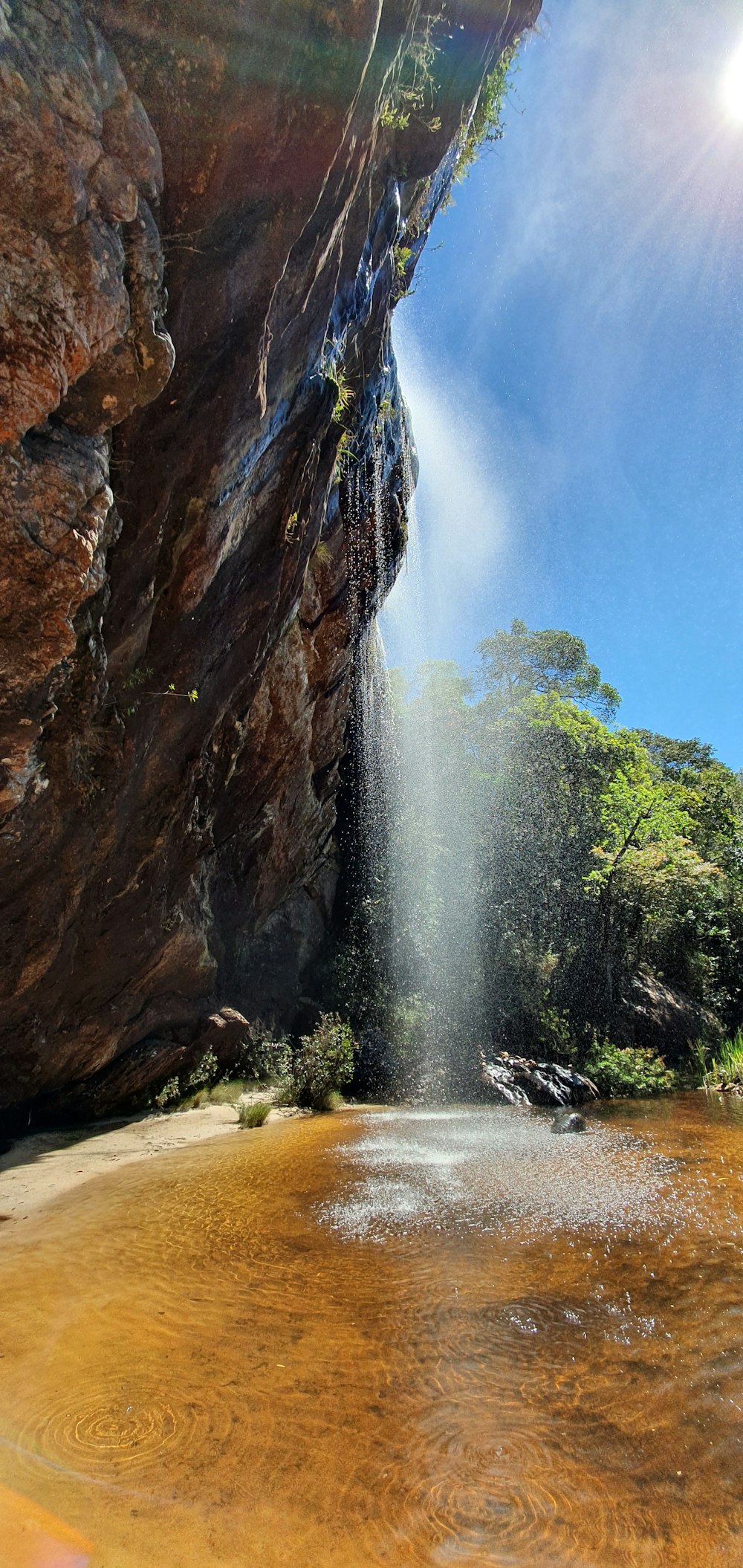 water falls between brown rocky mountain during daytime