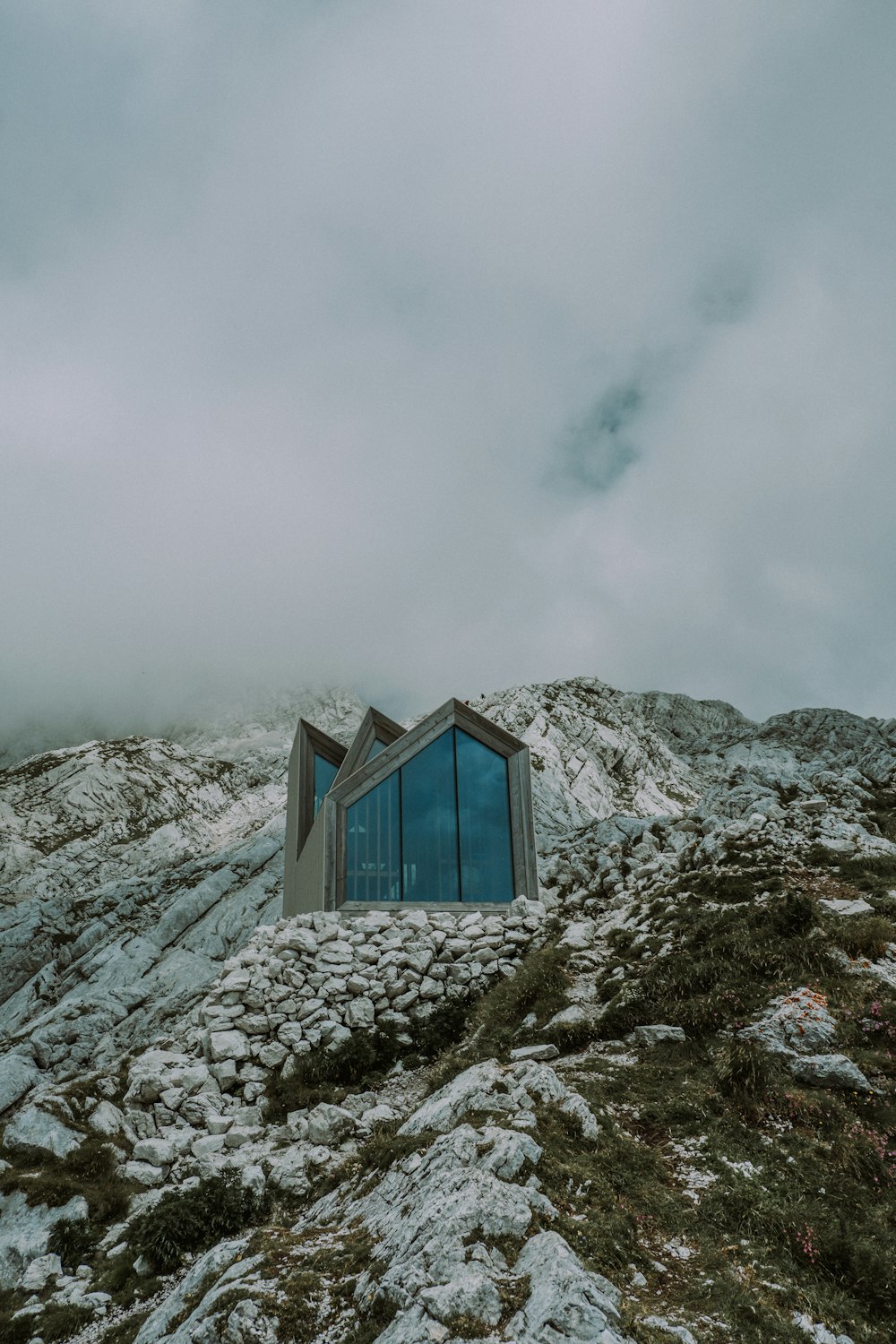 Casa di legno blu sulla montagna innevata sotto il cielo nuvoloso durante il giorno