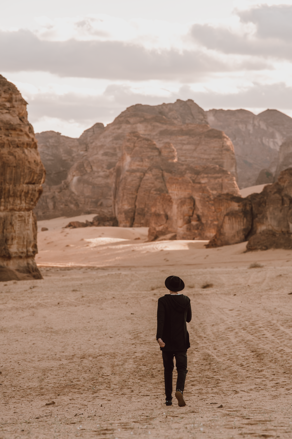 person in black jacket walking on brown sand during daytime