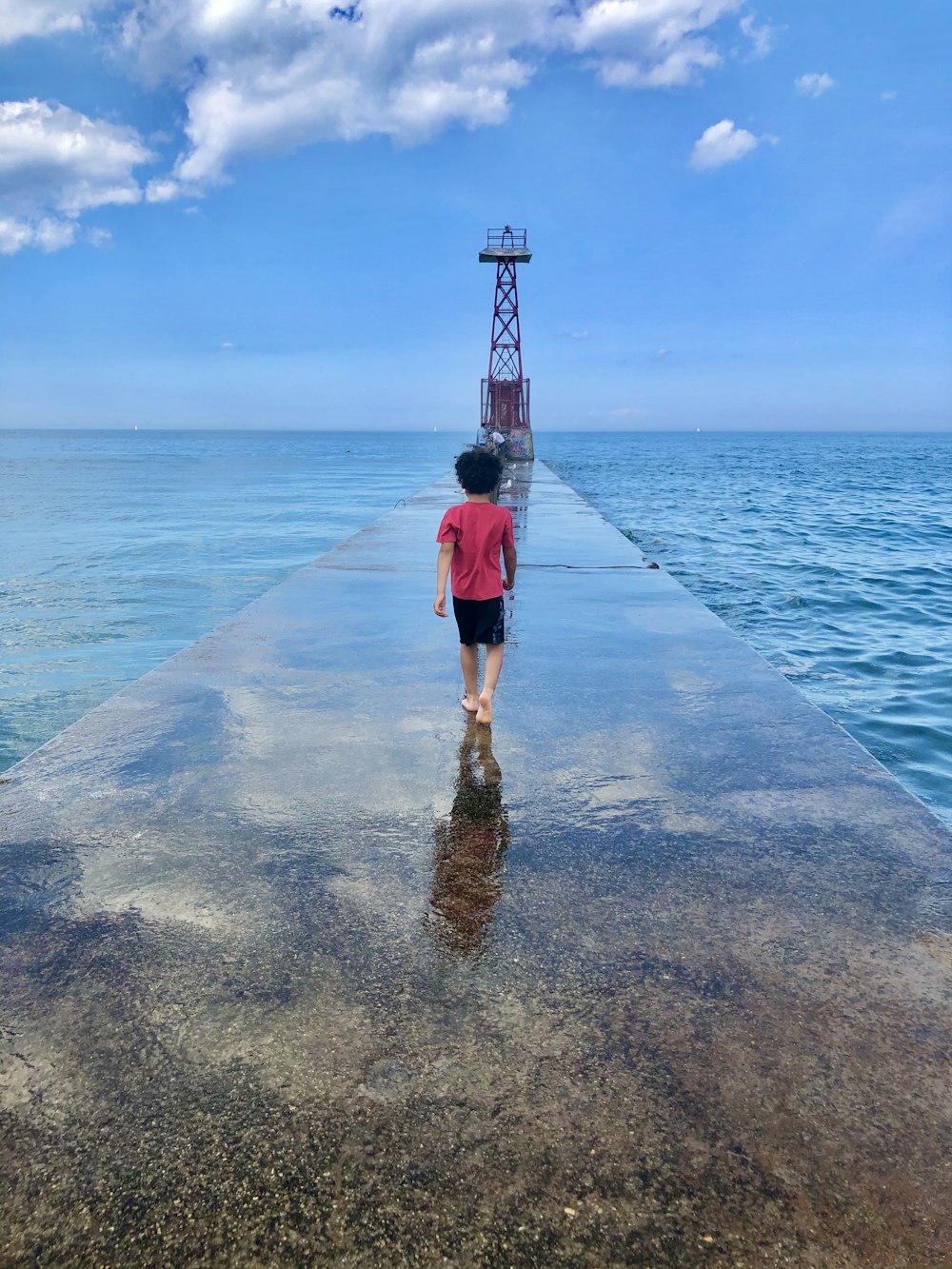 woman in black dress standing on concrete dock during daytime