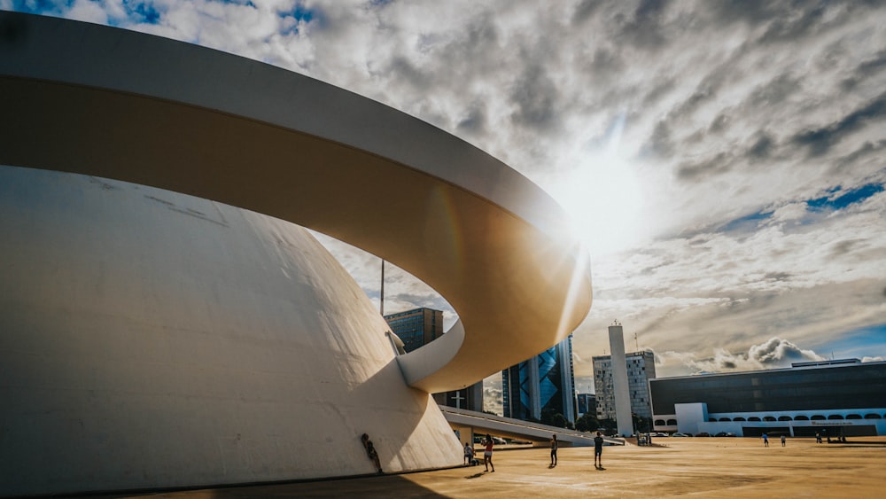 people walking on park near white concrete building under gray clouds during daytime