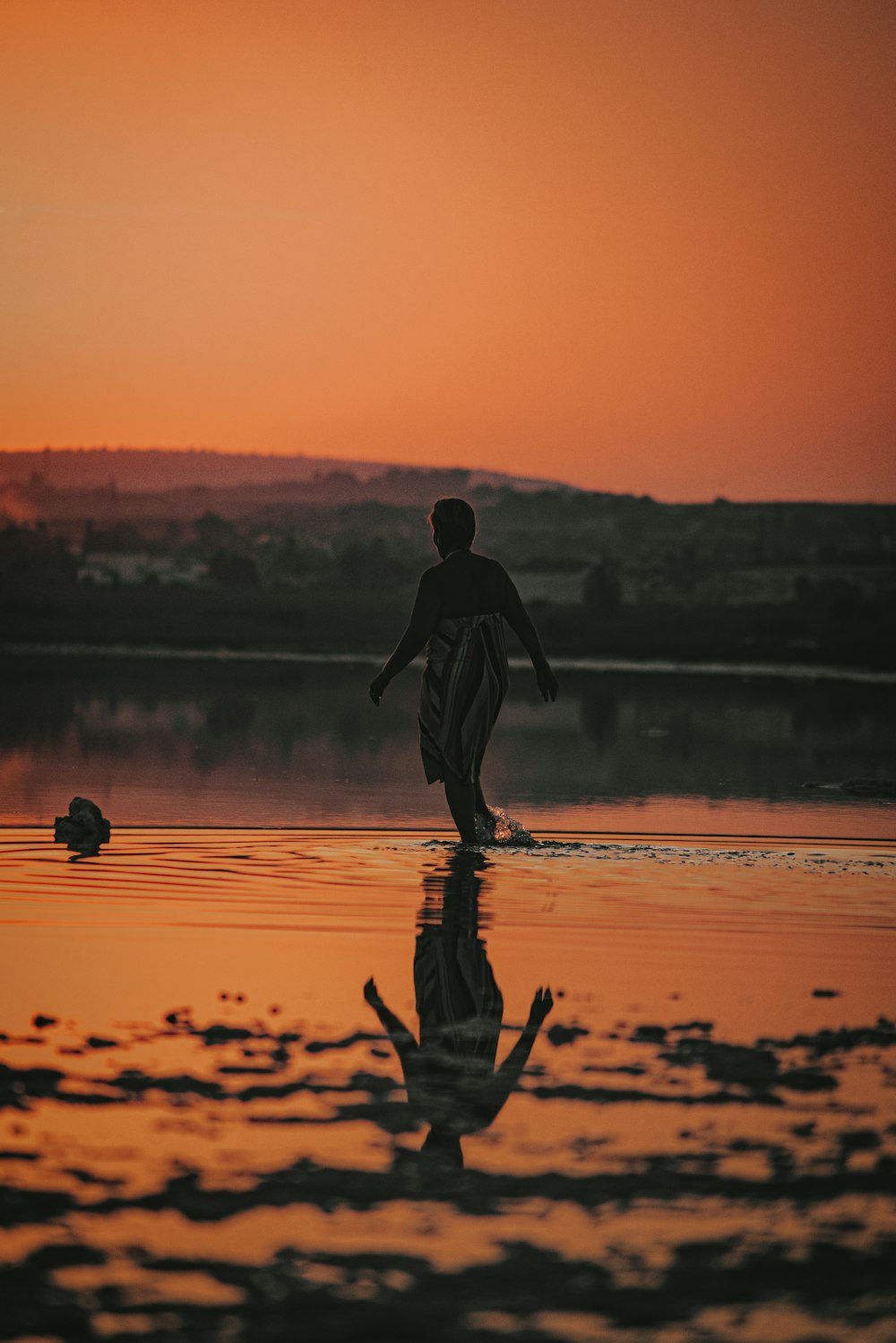 silhouette of man walking on water during sunset