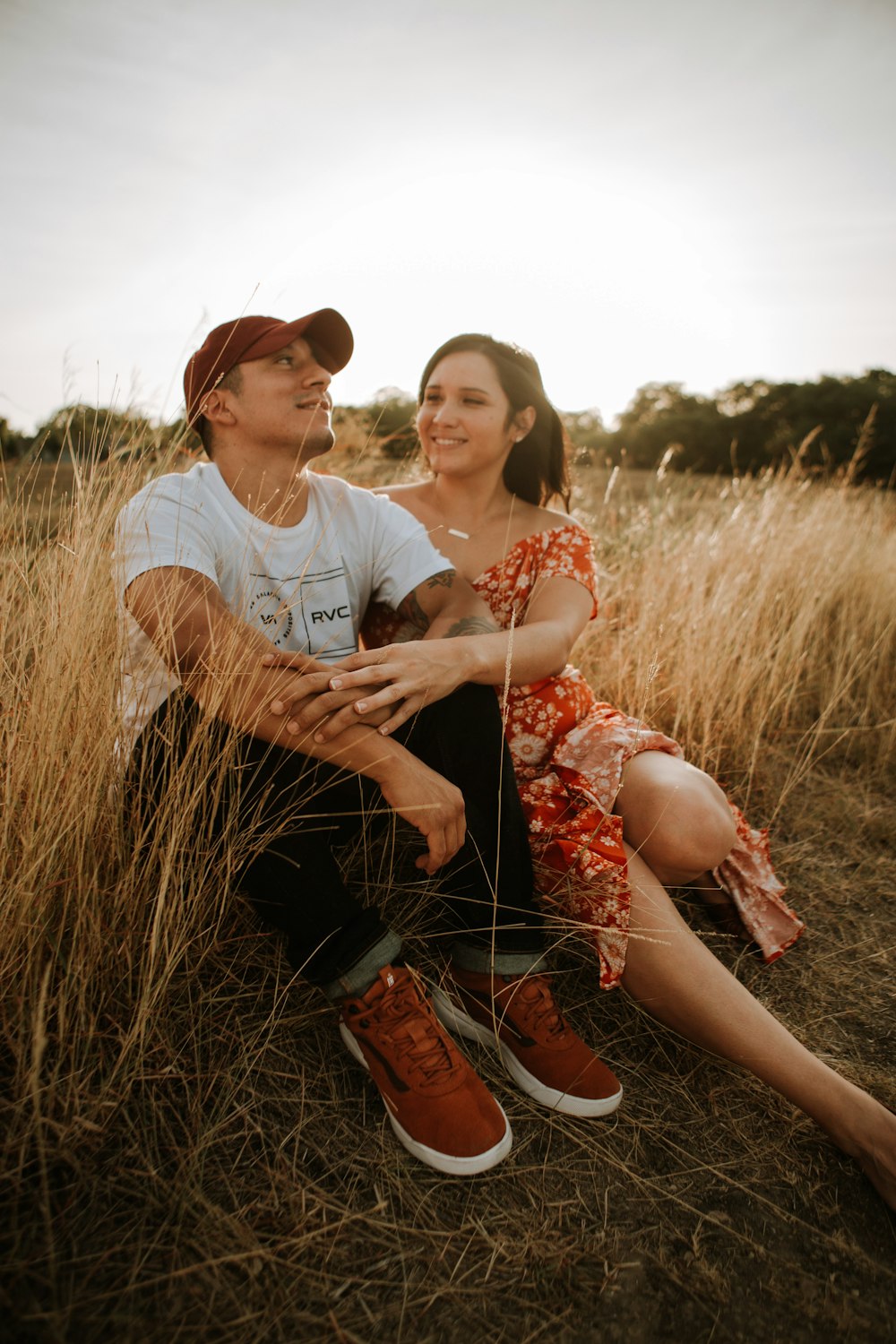 woman in white crew neck t-shirt sitting on brown grass field during daytime