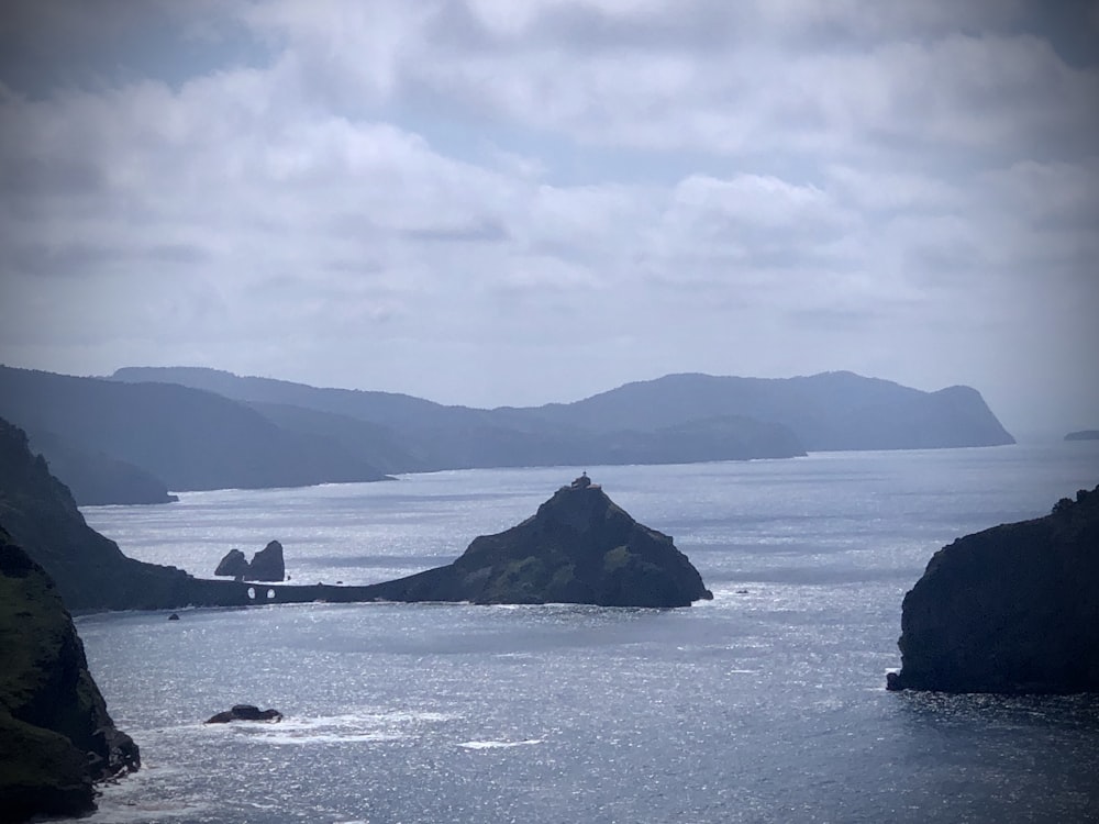 black rock formation on sea under white clouds during daytime