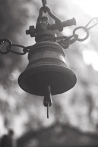 Close-up of temple bells hanging with soft sunlight filtering through.