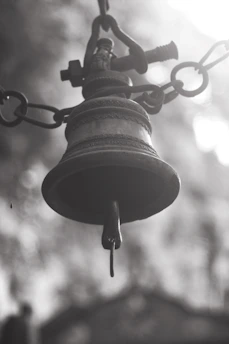 Close-up of temple bells hanging with soft sunlight filtering through.