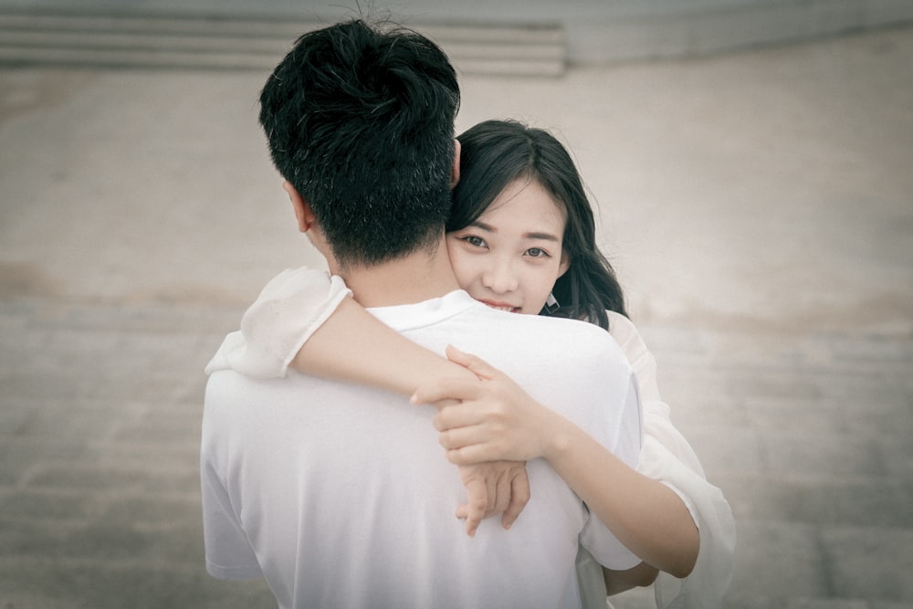man in white dress shirt hugging woman in white dress