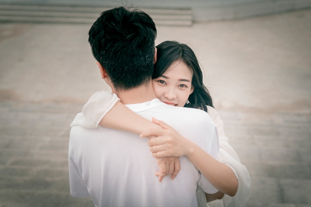 man in white dress shirt hugging woman in white dress