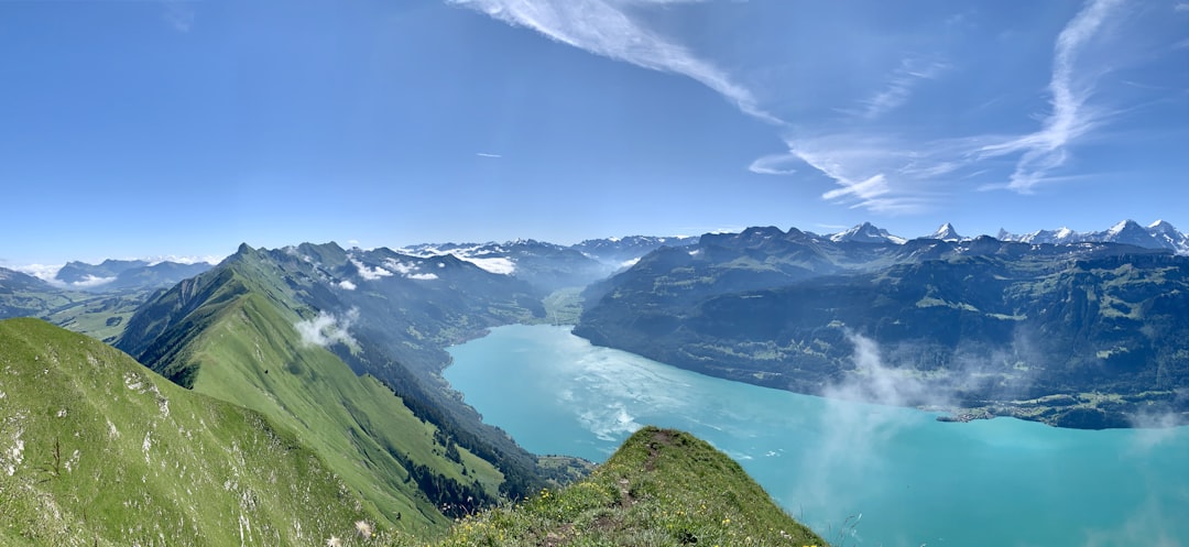 green mountains near lake under blue sky during daytime, mountain panorama over the lake of brienz.<p></figure>