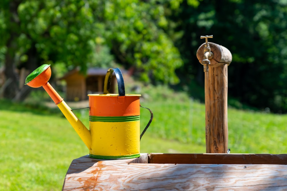 red and yellow watering can on brown wooden table