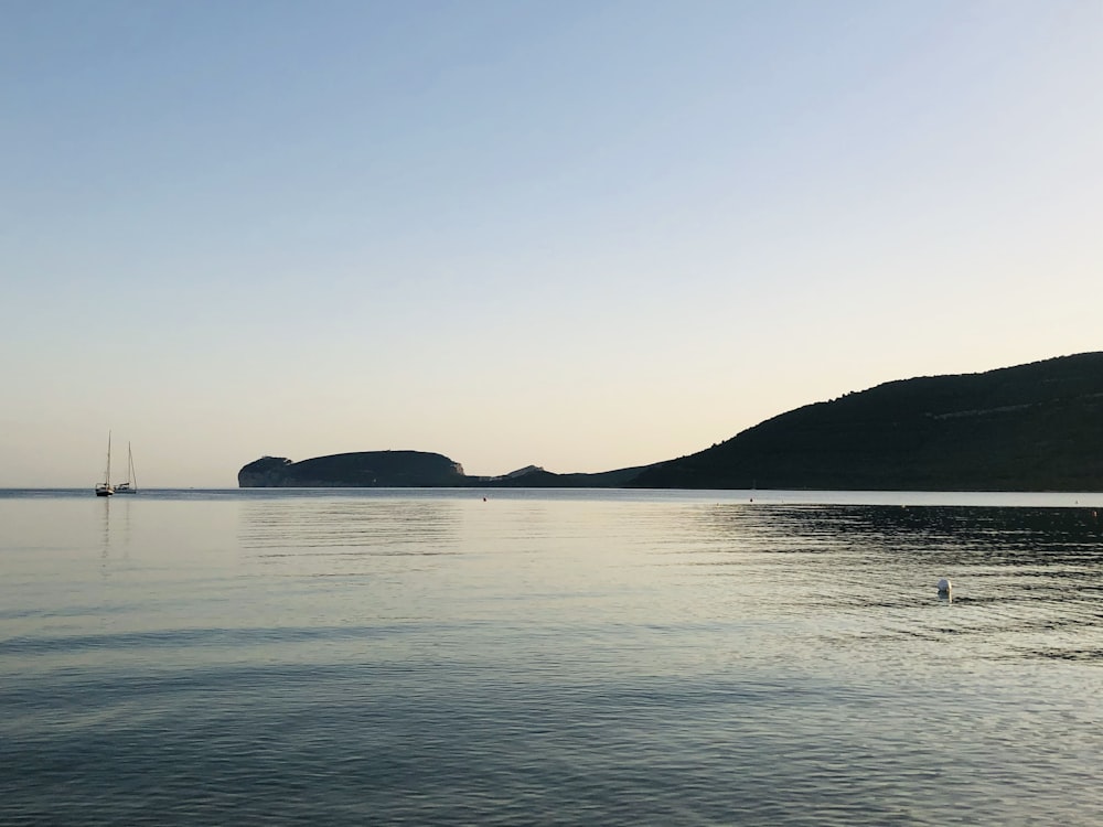 body of water near mountain during daytime