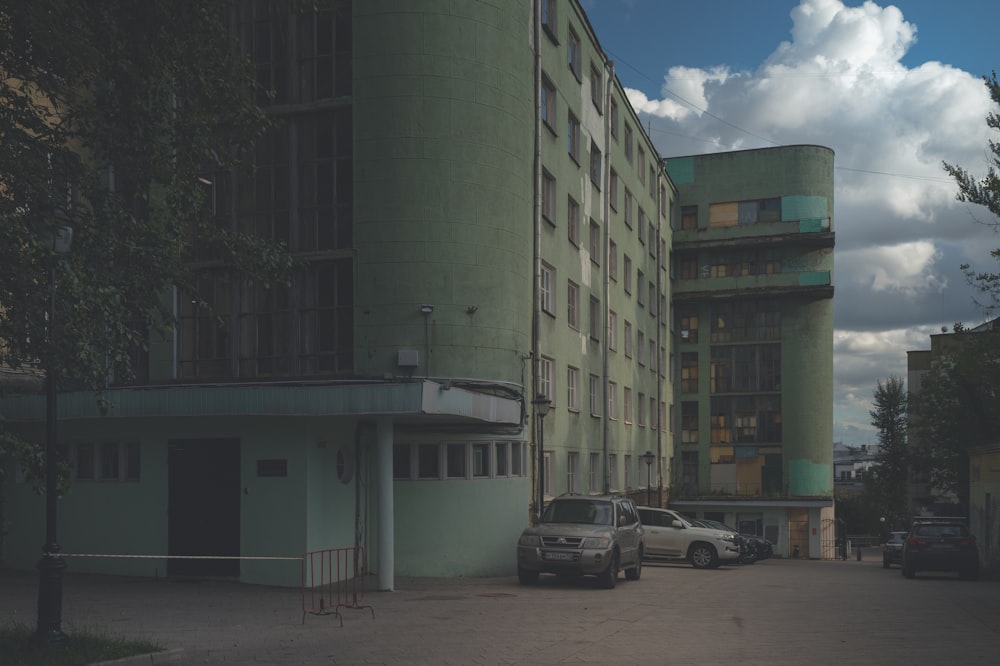 white car parked beside green concrete building during daytime