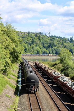black train on rail near green trees during daytime