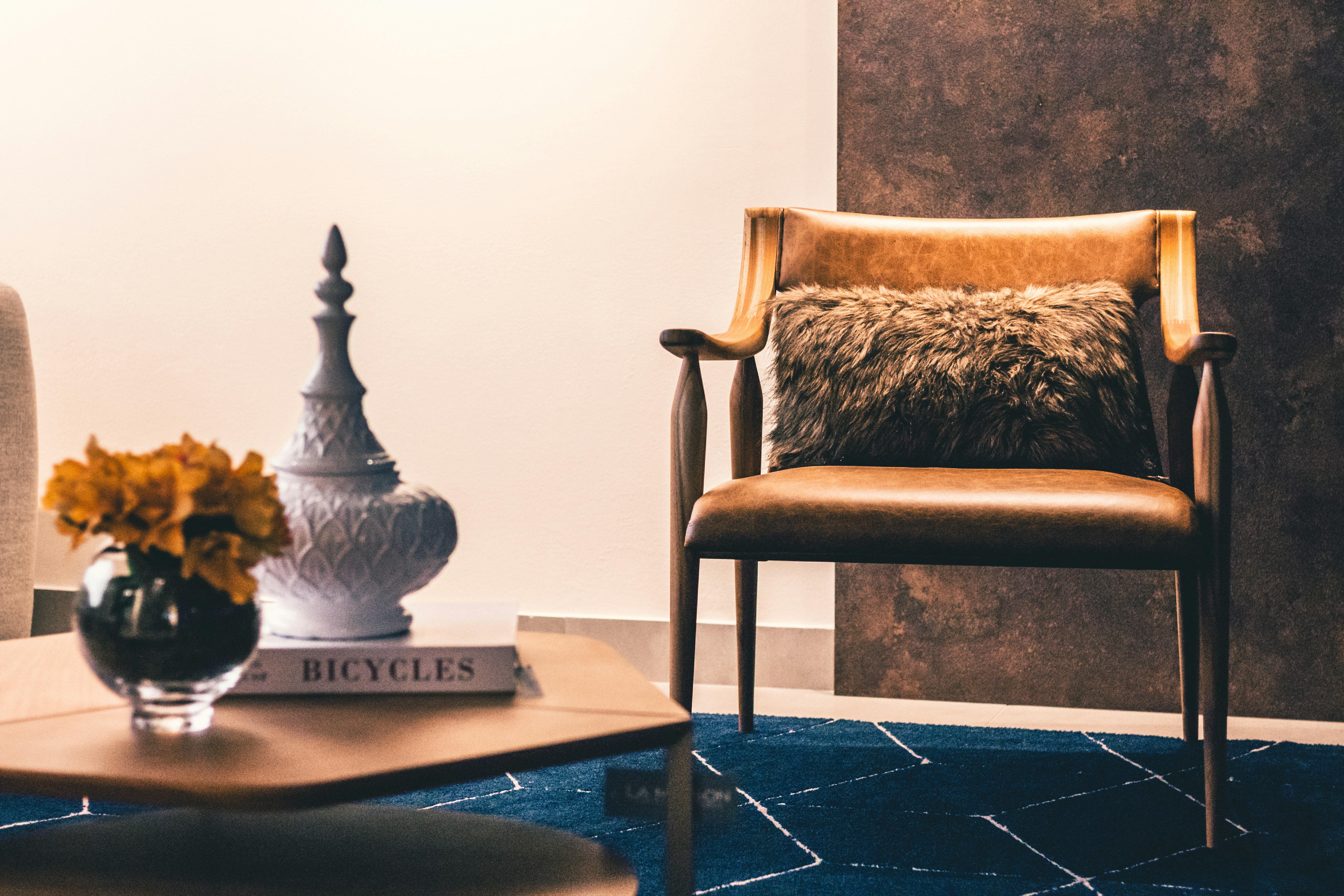 brown and black armchair beside white ceramic vase