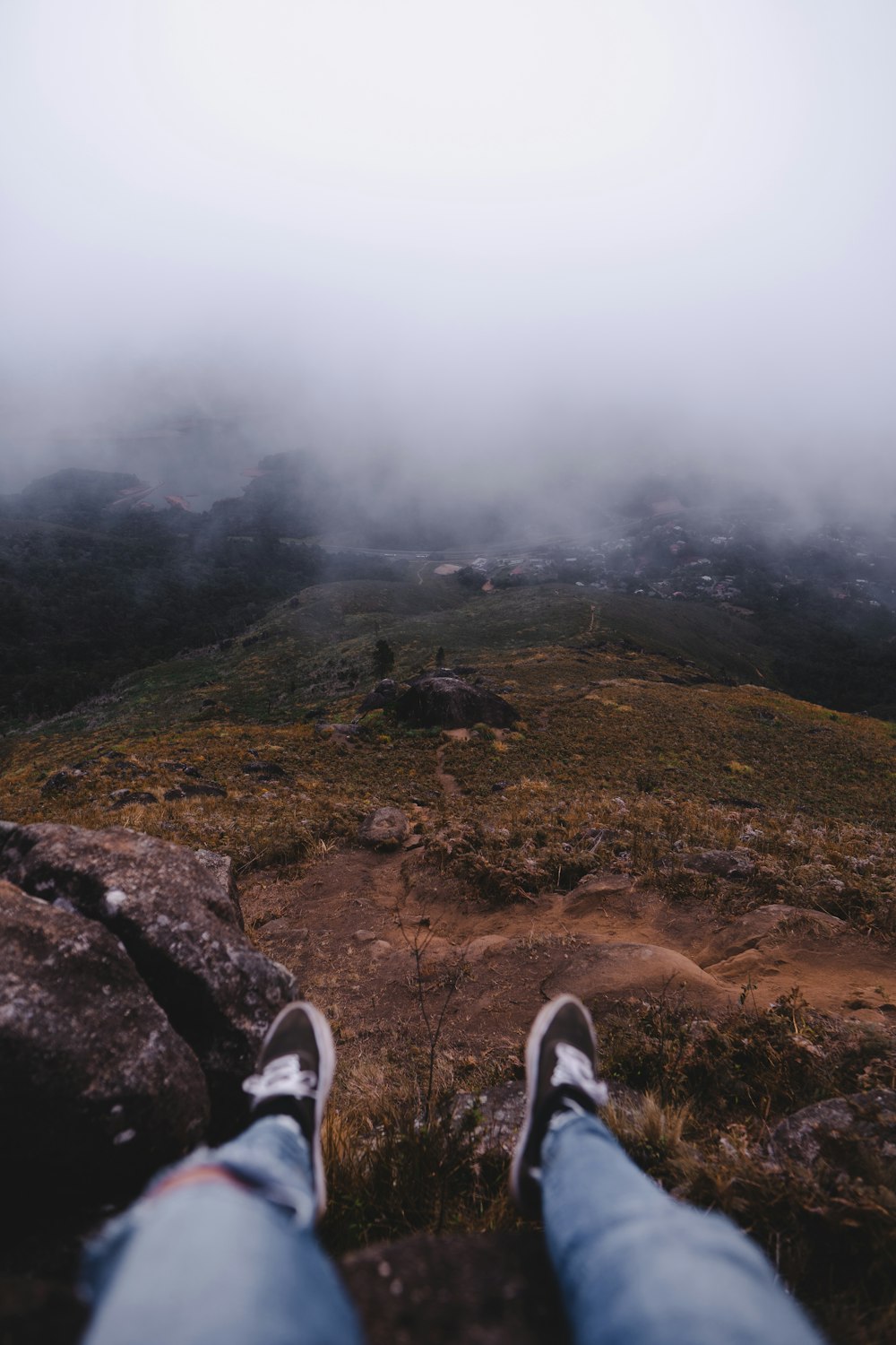 person in black and white sneakers standing on brown rock formation