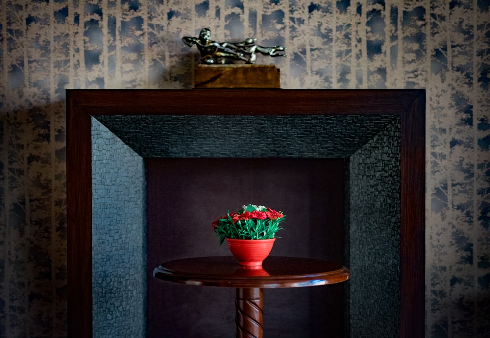red flowers in brown ceramic vase on brown wooden table