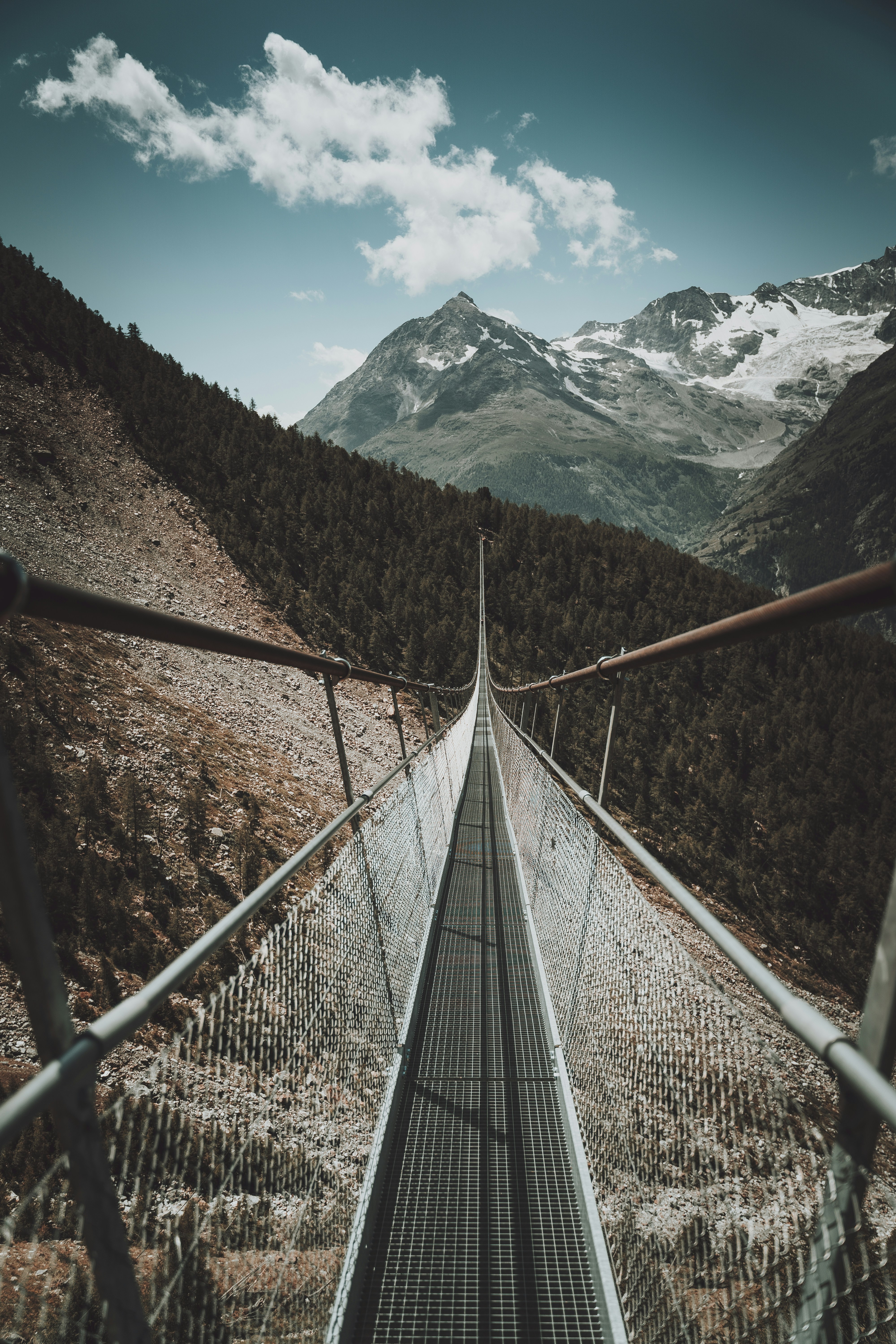 brown wooden bridge across snow covered mountain during daytime