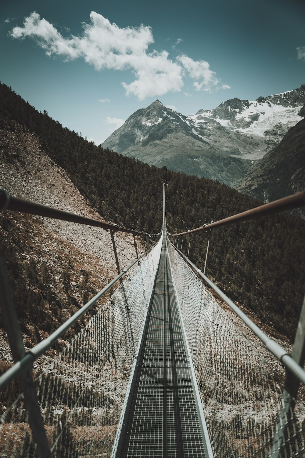 brown wooden bridge across snow covered mountain during daytime