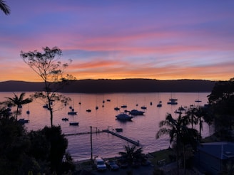 A tranquil harbor scene at sunset with calm waters.