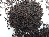 Organic black tea leaves spread out on a traditional woven mat.