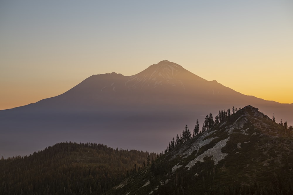 the sun is setting over a mountain range