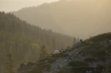 A peaceful glamping tent nestled among lush mountains under a soft golden sunset.