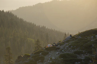 A serene mountain landscape at sunrise with a luxury tent set up for travelers.
