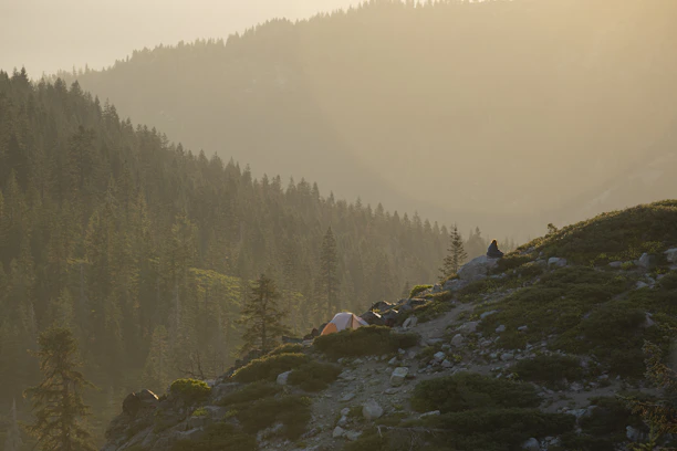 A serene mountain landscape at sunrise with a luxury tent set up for travelers.