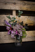 Delicate floral arrangement in a vintage mason jar with subtle rustic accents.