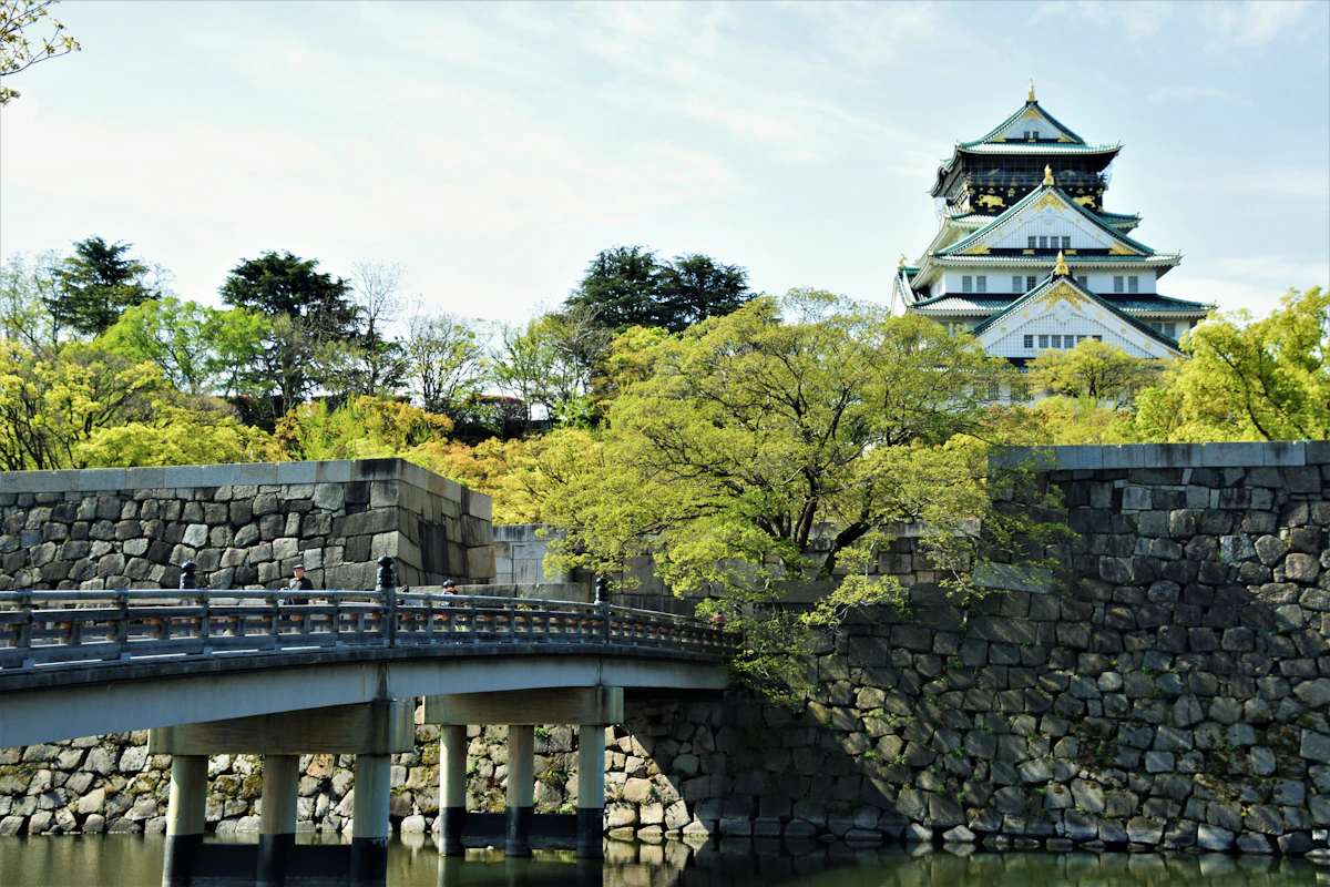 Osaka Castle rising above stone walls, trees and a moat