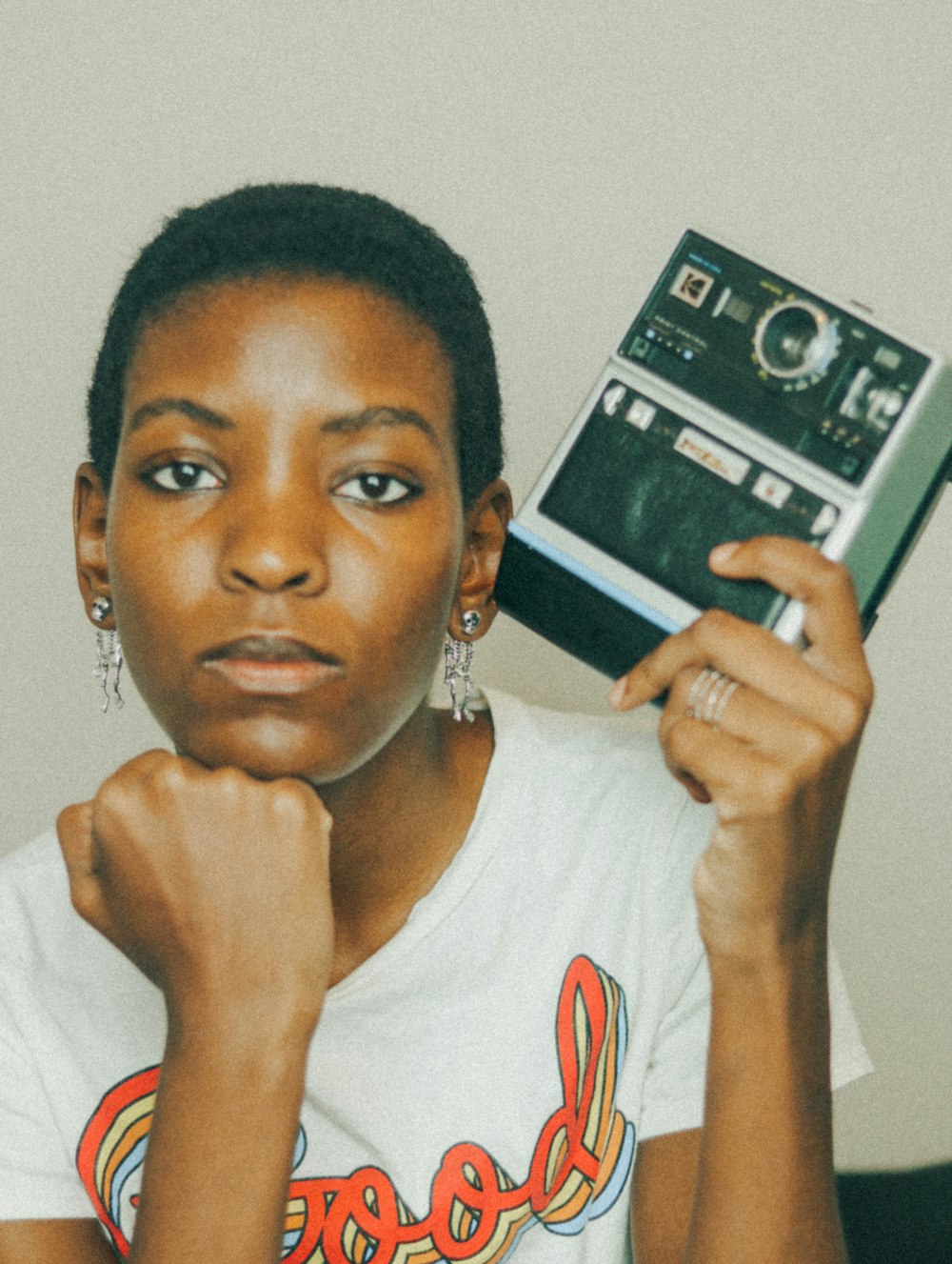 woman in white and red crew neck shirt holding black and white camera