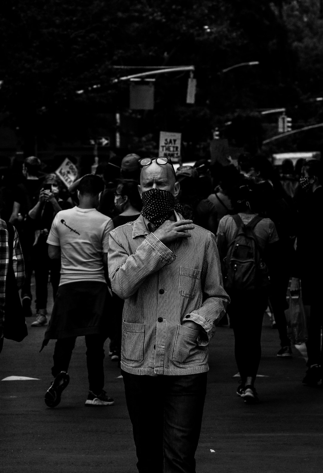 grayscale photo of man in jacket and knit cap standing on street