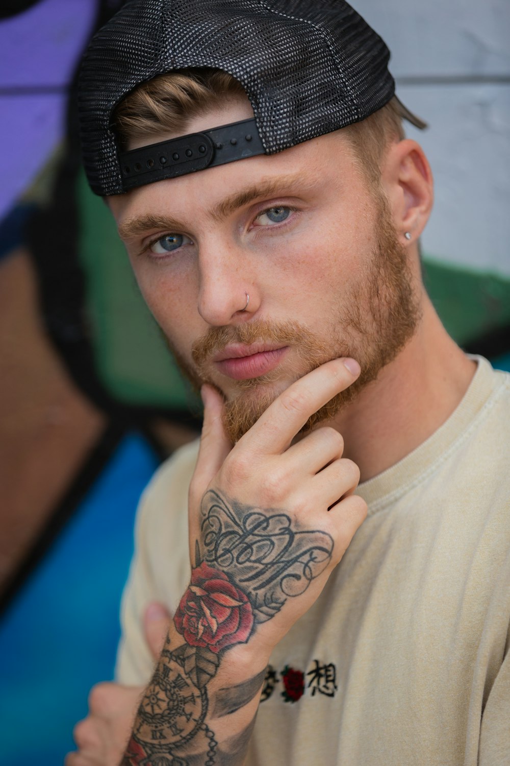 man in white crew neck shirt with black and red floral tattoo on his left hand