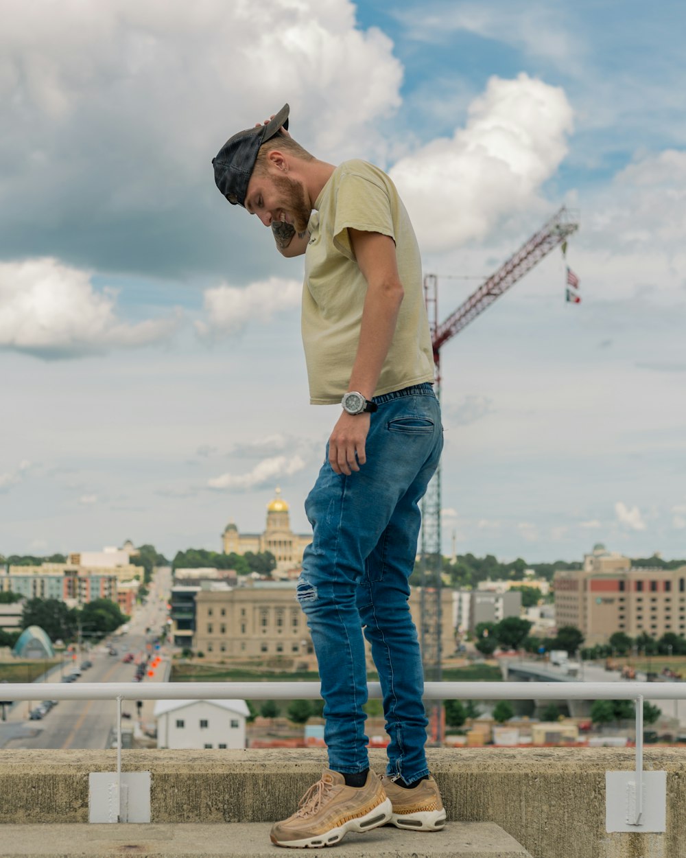 man in brown polo shirt and blue denim jeans standing on top of building during daytime