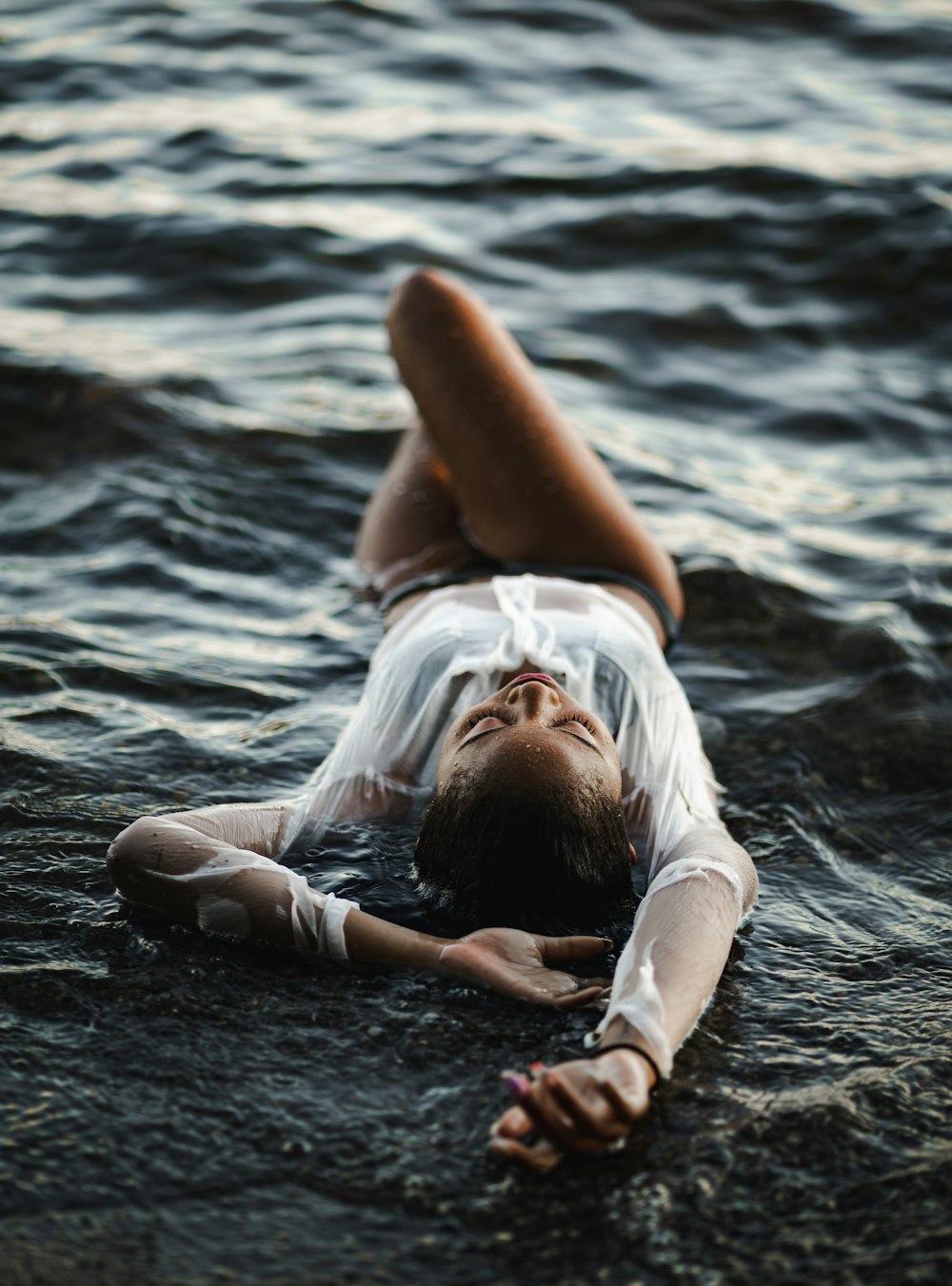 femme en chemise blanche allongée sur la plage