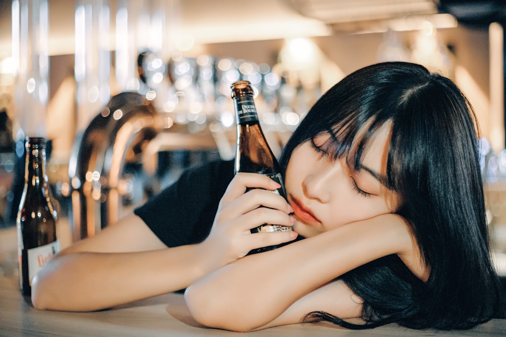 woman in black tank top holding brown glass bottle