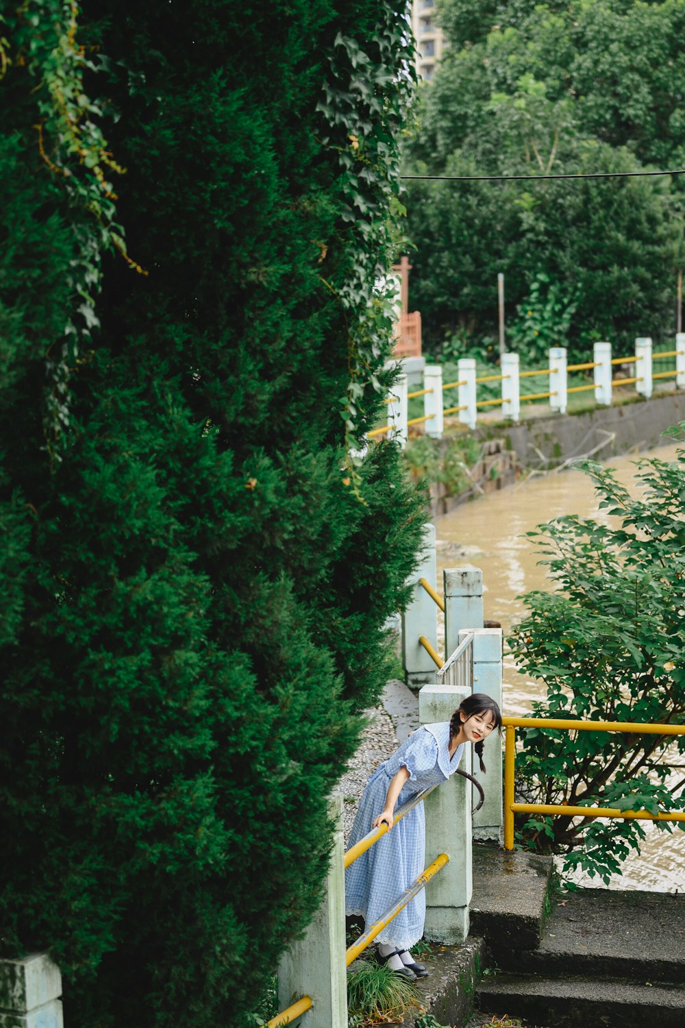 woman in blue jacket and blue denim jeans standing on brown wooden bridge